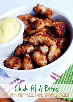 a white bowl filled with tater tots next to a cup of mustard sauce