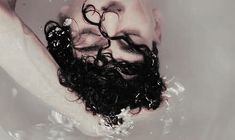 a man with curly hair and beard in a bathtub holding his head above the water