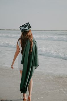 a woman walking on the beach with a green blanket over her head