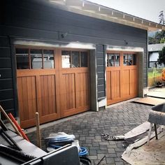 two brown garage doors are open on the side of a house with brick pavers