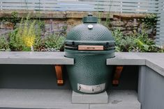 a big green egg sitting on top of a cement bench