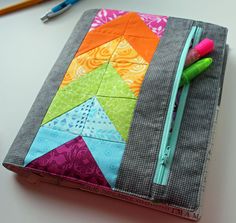 a small notebook cover made out of fabric, with markers and pencils in it