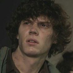 a close up of a person with curly hair and an unkempt look on his face