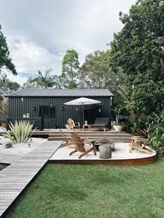 a patio with chairs and an umbrella in the middle of it, surrounded by greenery