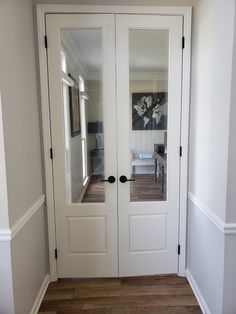 two white doors with mirrors on them in a room that has hardwood floors and hard wood flooring