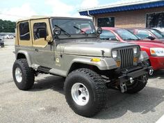 the jeep is parked in front of other cars