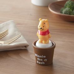 a winnie the pooh cup sitting on top of a table next to a fork and knife