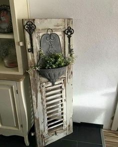 an old shuttered door is holding a planter with flowers in it and hanging on the wall