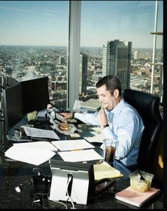 a man sitting at a desk in front of a window with a view of the city