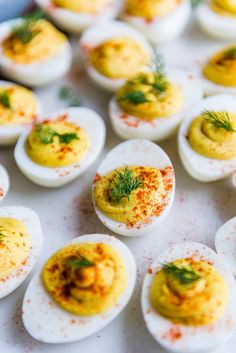 an assortment of deviled eggs with mustard and dill sprinkled on them