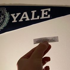 someone is holding up a business card in front of a sign that says yale