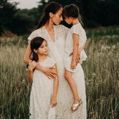 mother and two daughters standing in tall grass with their arms around each other as they look at each other