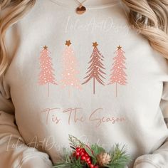 a woman wearing a christmas sweater with pine trees on it and the words tis the season