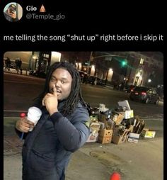 a man with dreadlocks talking on his cell phone while standing next to a pile of junk