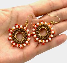 a hand holding a pair of beaded earrings