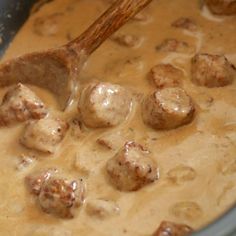 meatballs and gravy being stirred in a pot