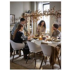 a group of people sitting around a dining room table with food and drinks on it