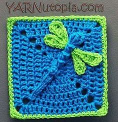 a crocheted square with a green bow on the front and blue squares on the back