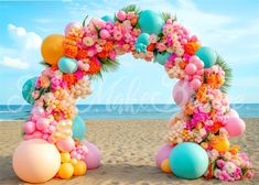 an arch made out of balloons and flowers on the beach