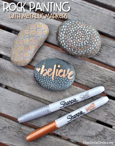 rock painting with metallic marker markers and pens on a wooden table next to some rocks