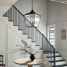 a table with a vase on top of it next to a stair case