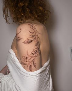 the back of a woman's shoulder with flowers on it and leaves coming out