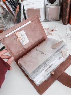 a person is holding an open book on a table with other items in the background