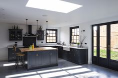 a kitchen with black cabinets and an island in the middle is lit by sunlight coming through the windows