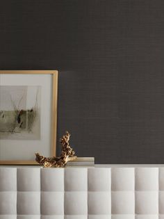 a white shelf sitting next to a framed photo on top of a wooden table in front of a gray wall