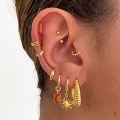 a woman wearing gold ear cuffs and earrings