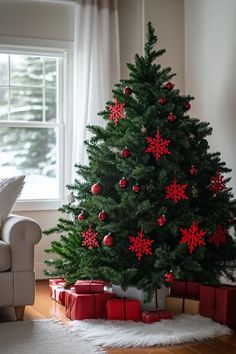 a christmas tree with red and silver ornaments in a living room next to a white couch