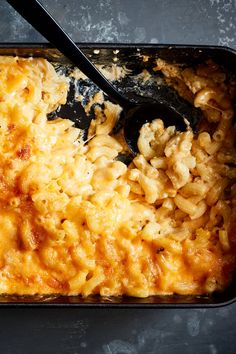 macaroni and cheese in a casserole dish with a black serving spoon