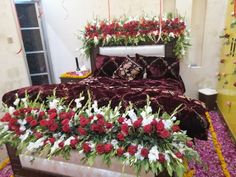 a bed with red and white flowers on the headboard, along with other decorations