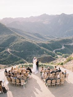 an outdoor ceremony with chairs and mountains in the background, overlooking a valley filled with greenery