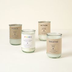 three candles with labels on them sitting next to each other in front of a white background