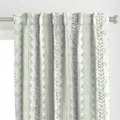 a curtain with green leaves on it in front of a window