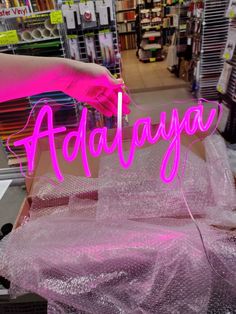 a pink neon sign that says adidaya in the middle of a store aisle