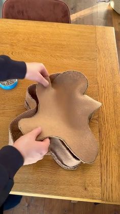 a child is making an apple shape out of cardboard on a wooden table with a blue brush