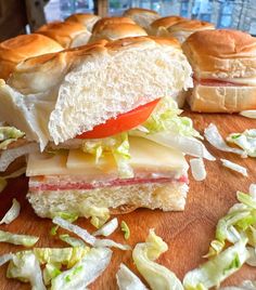 a sandwich cut in half sitting on top of a cutting board next to other sandwiches