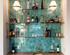 a bathroom sink sitting under two lights next to a shelf with liquor bottles on it