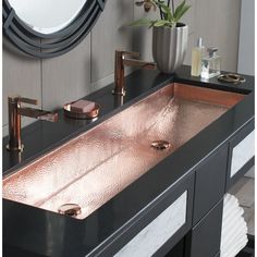 a bathroom sink sitting under a mirror next to a vase with flowers on top of it