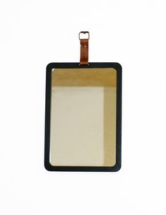 a black and brown square shaped frame hanging on a white wall with a leather strap