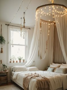 a bed with white curtains and lights hanging from it's headboard in front of a window