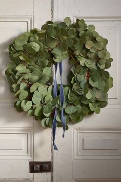 a wreath hanging on the front door of a house with blue ribbon tied around it