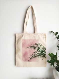 This hand printed cotton tote  bag is made for your everyday stylish life. The burgundy red background and the palm leaves  on the bag are bold and edgy yet they are sharp and lots of fun. You can carry it all day long, from morning to evening. It's strong, comfortable and spacious and fits a great deal of things. This reusable tote bag is ideal for carrying books, transporting grocery shopping or for use on any day out. Makes you feel cute and vibrant.Canvas is a very durable material and i lov Painted Shopping Bag, Painting On Cotton Bags, Everyday Rectangular Bag With Plant Print, Rectangular Canvas Bag With Eco-friendly Ink For Summer, Hand Printed Canvas Tote Bag, Everyday Tote Bag With Plant Print, Cotton Tote Bag With Plant Print, Hand Printed Canvas Bag For Everyday Use, Cotton Bags With Plant Print For Daily Use