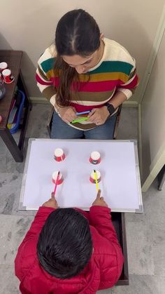 two people sitting at a table with toothbrushes in their hands and one person writing on a piece of paper