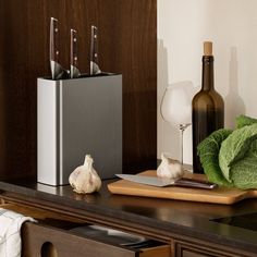 an assortment of kitchen utensils and garlic on a counter top next to a bottle of wine