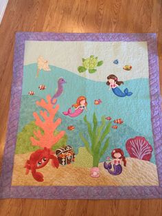 a child's quilt with mermaids and sea animals on it