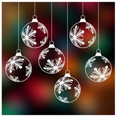 three christmas ornaments hanging from strings against a blurry background with snowflakes on them