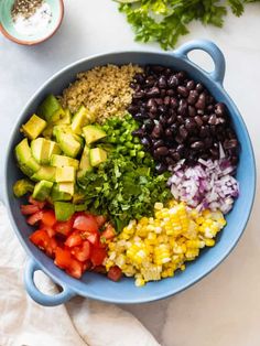 a bowl filled with black beans, avocado, corn and other vegetables